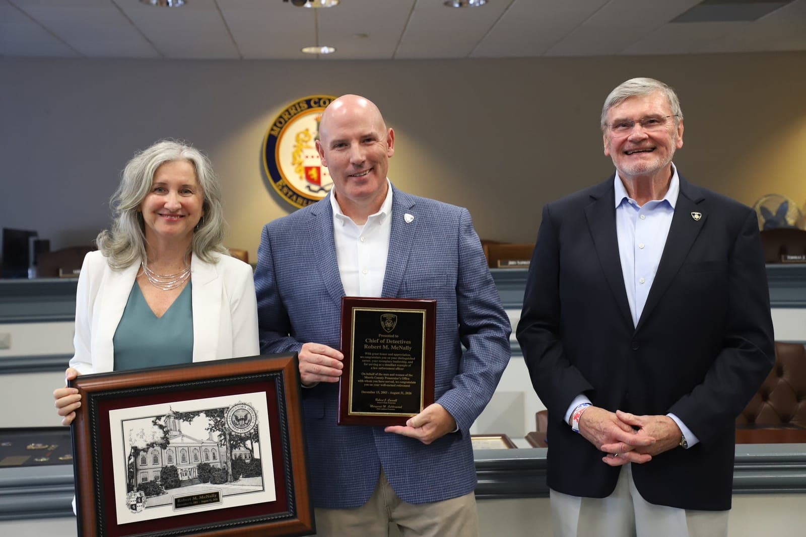 Chief of Detectives Robert McNally, center, is presented with a retirement plaque and keepsake at his retirement ceremony.