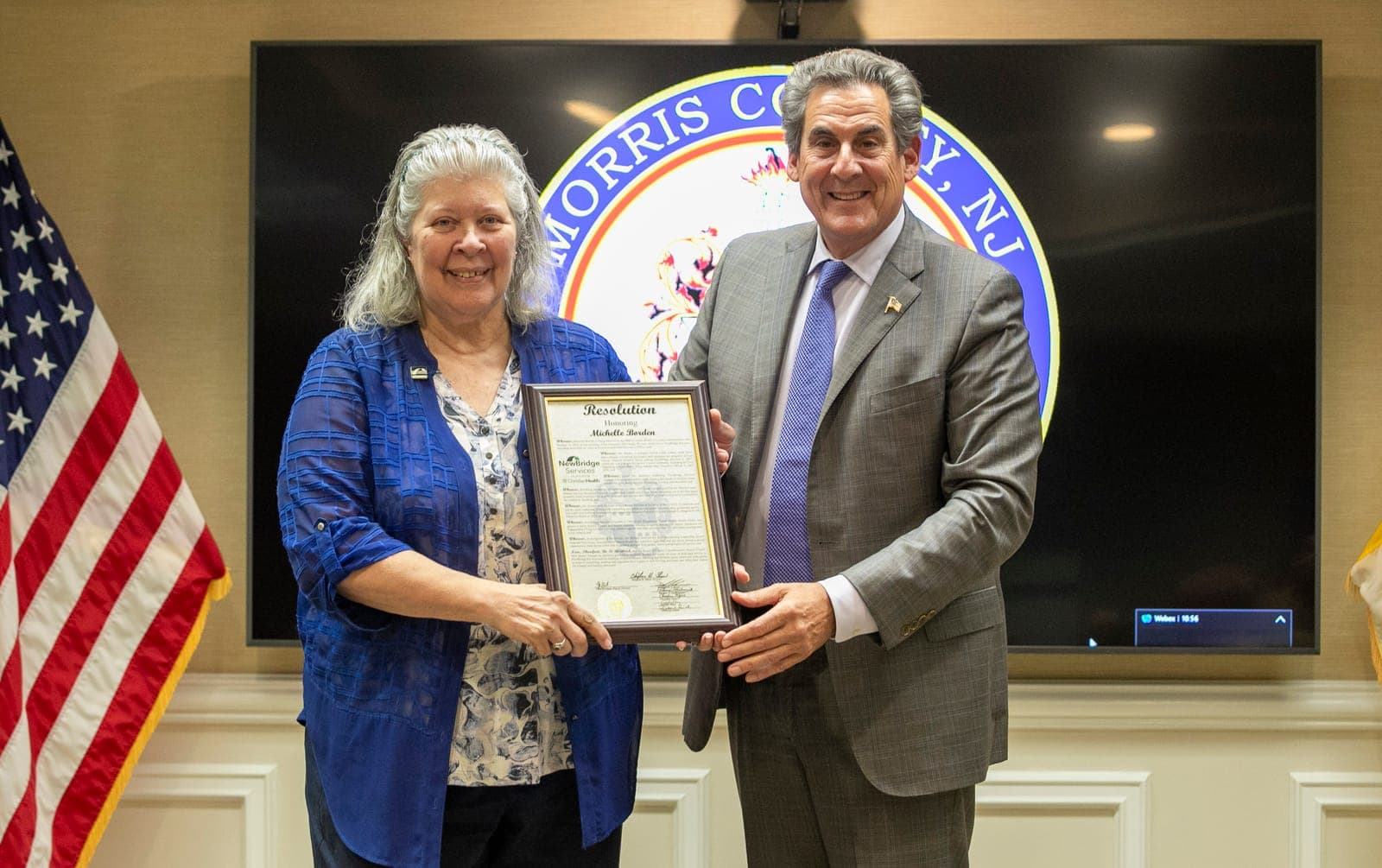 Commissioner Director Stephen H. Shaw presents a resolution of honor to Michelle Borden, who retired as president and CEO of NewBridge Services.